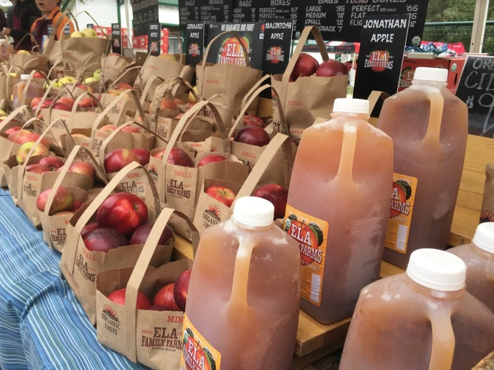 jugs of cider and bags of red delicious apples at Denver farmers market